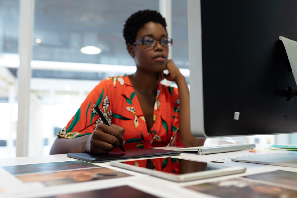 Female graphic designer working on graphic tablet at desk
