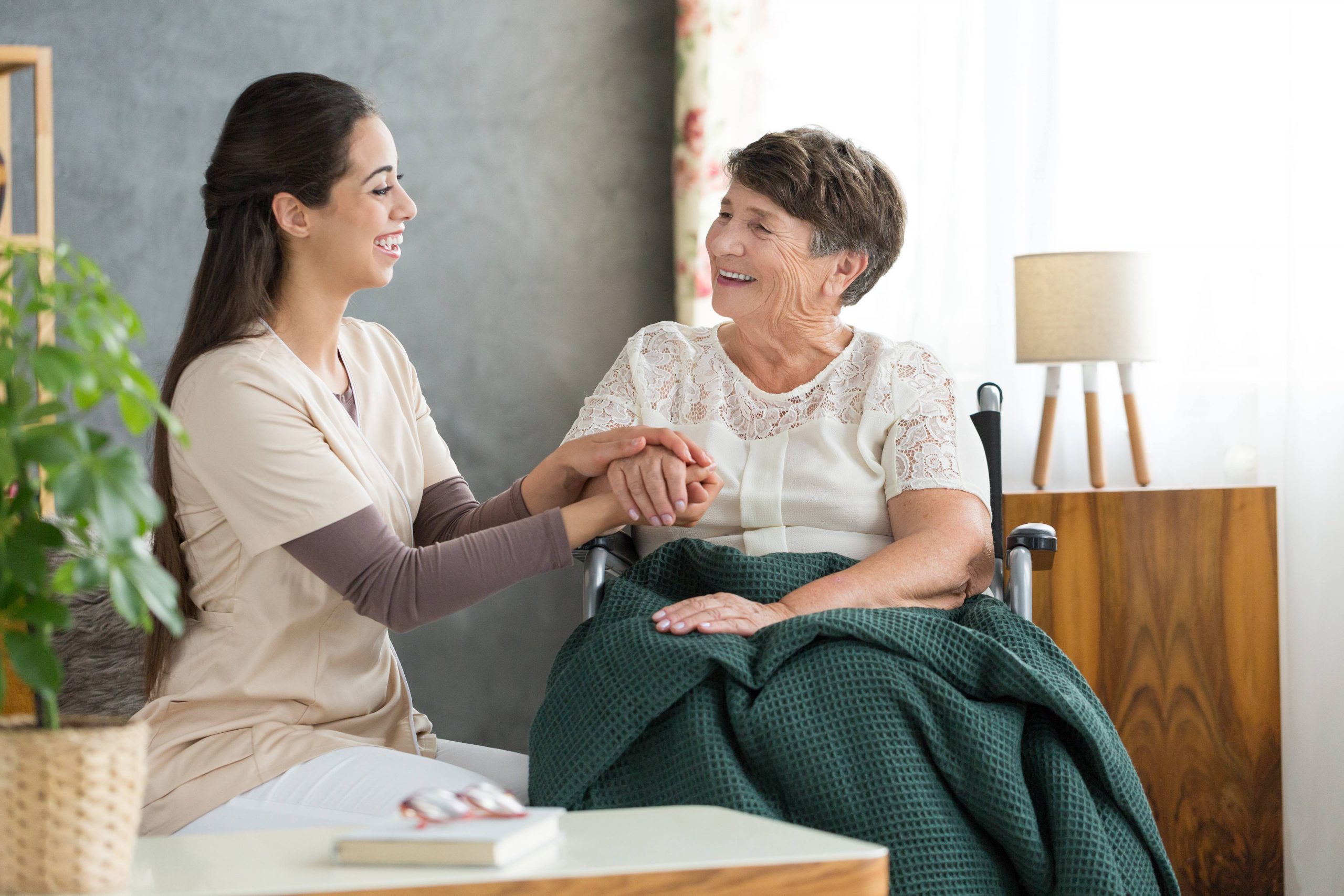 Aide holding hand of older woman