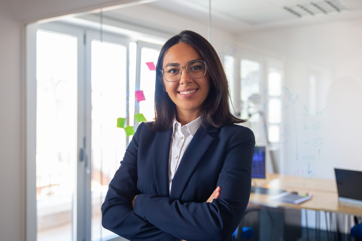 Legal assistant standing in office with arms crossed