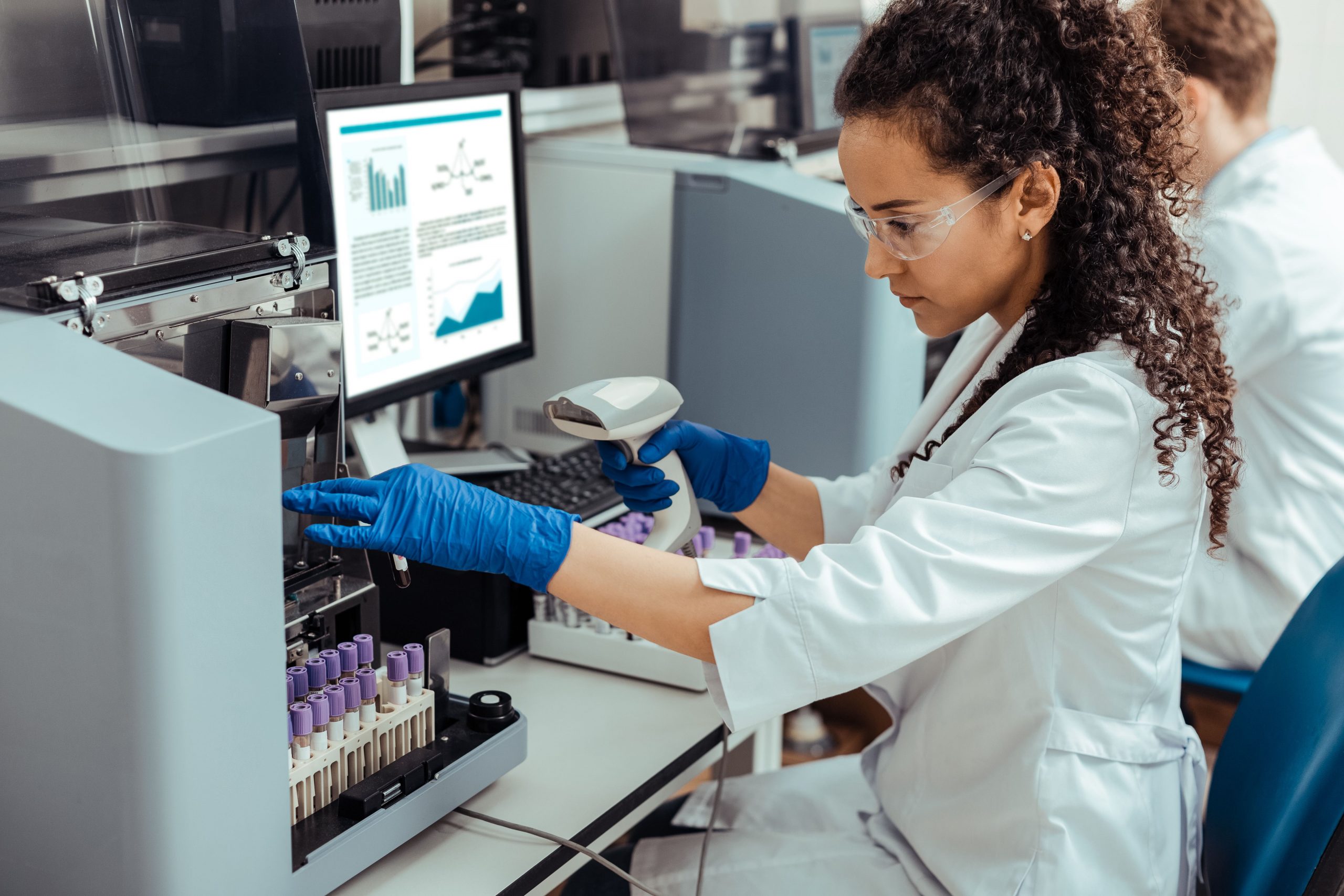 Medical lab assistant sitting at desk working with test tubes