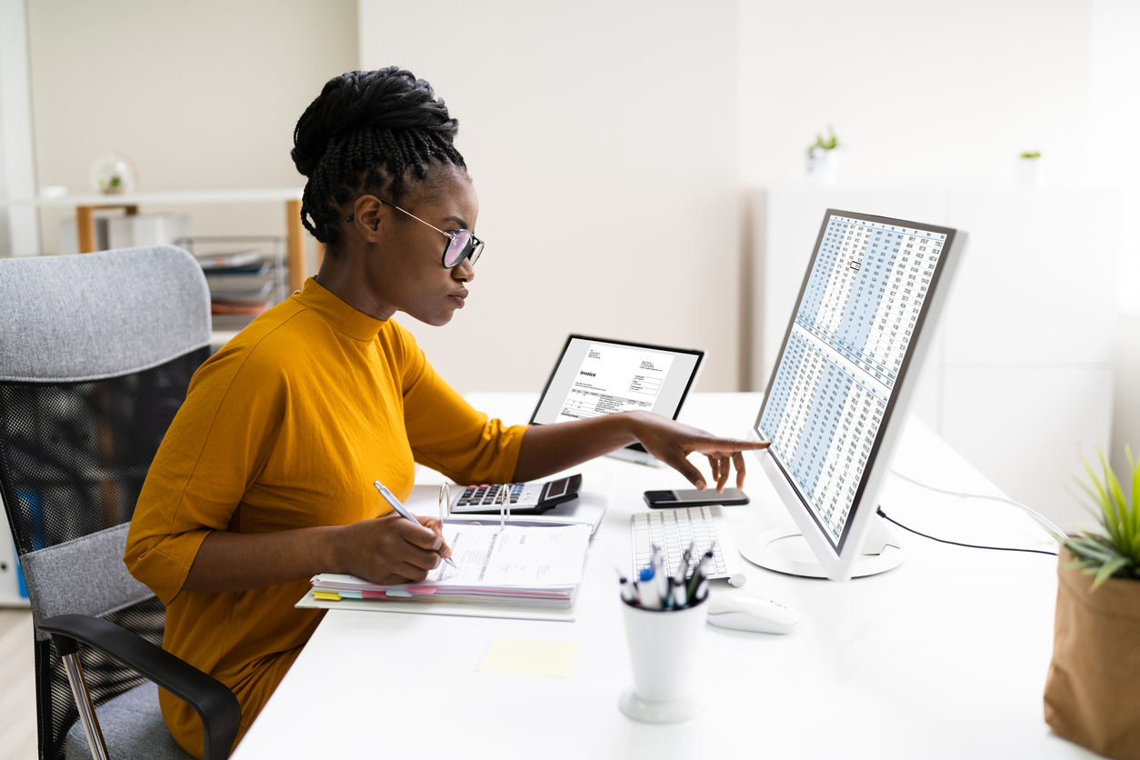 Accounting clerk taking notes while working on laptop