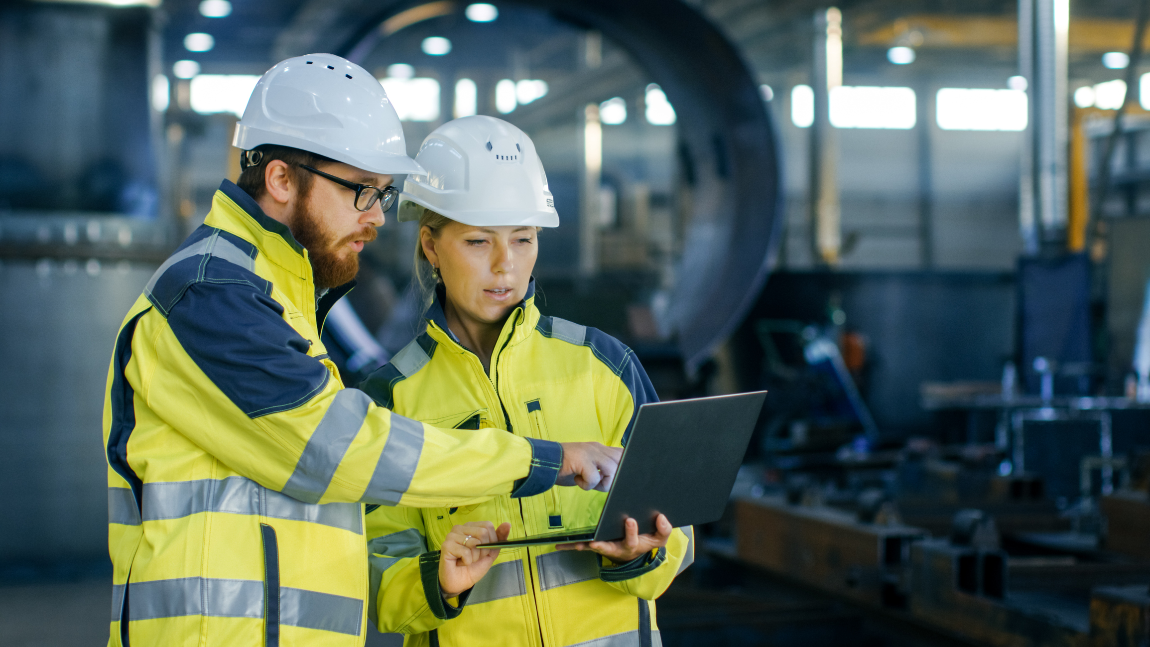 Safety officers in hard hats conferring with each other in factory