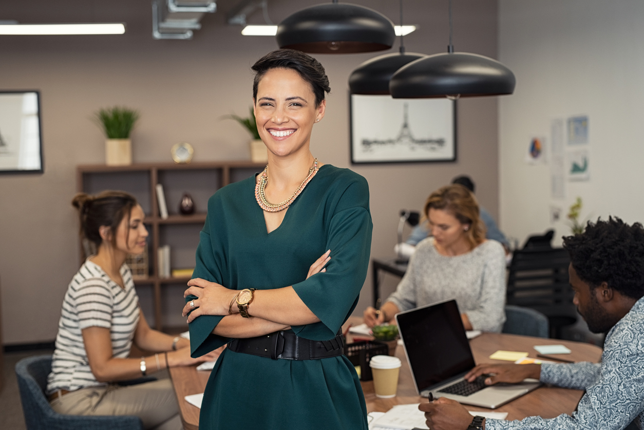 Woman standing in front of table where colleagues are working