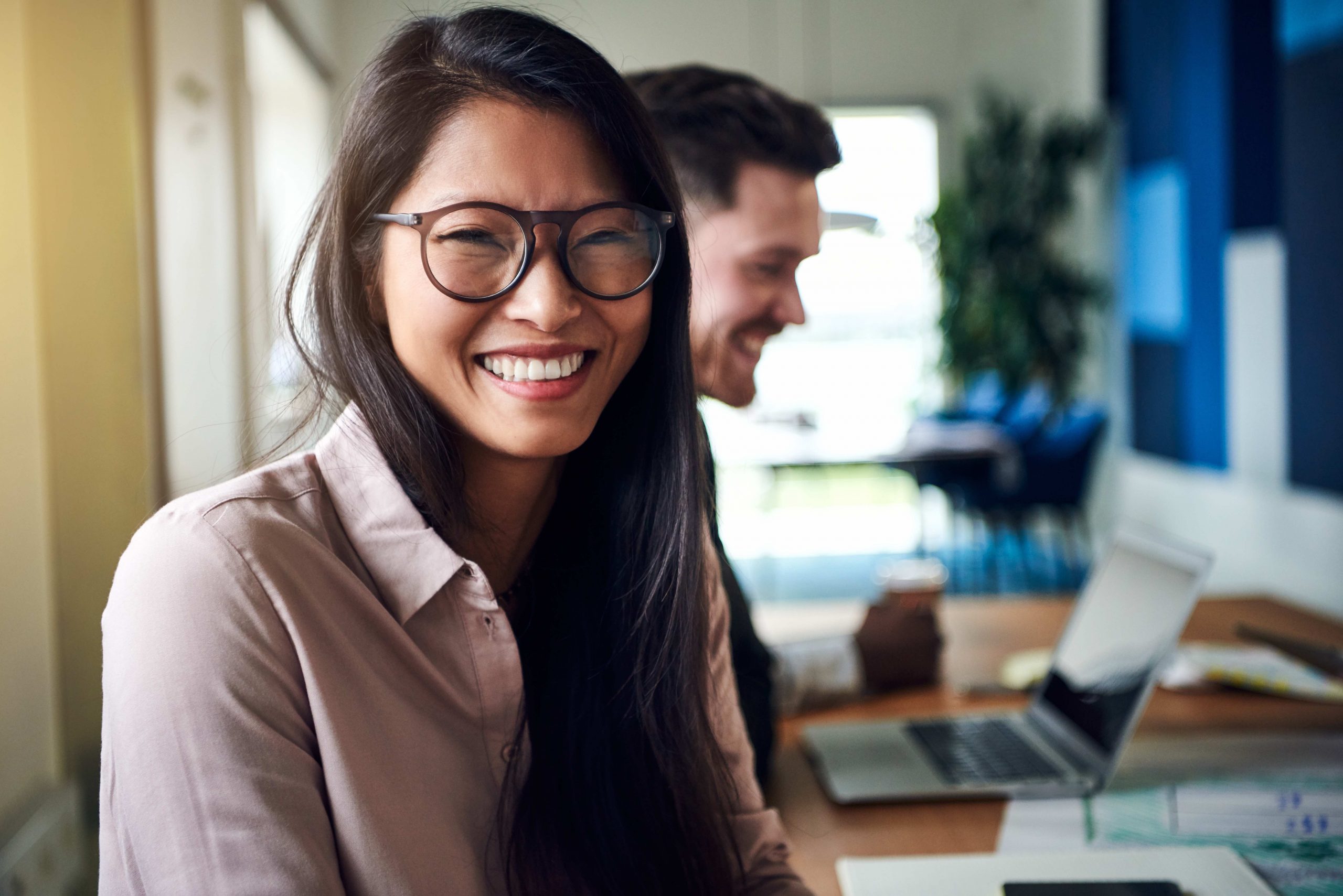 Smiling woman sitting at desk near colleague